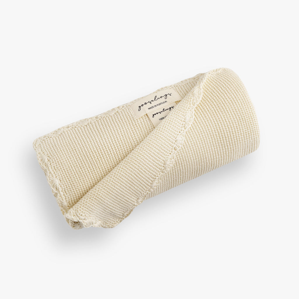 Cotton Knit Baby Blanket in Ivory  rolled up. The Gooselings label is shown for detail