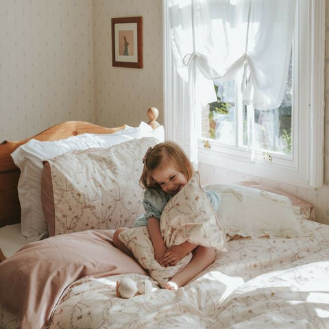 Bows & Butterfly Kisses Toddler Pillow in Pink. Child hugging pillow on top of bed,