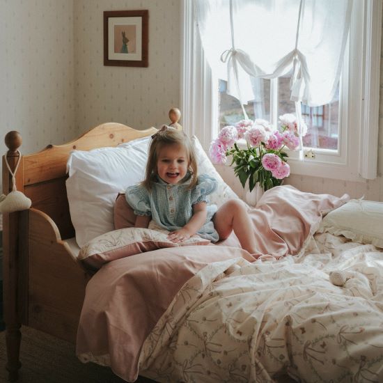 Bows & Butterfly Kisses Twin Set in Pink displayed on bed. Child is smiling and cozy