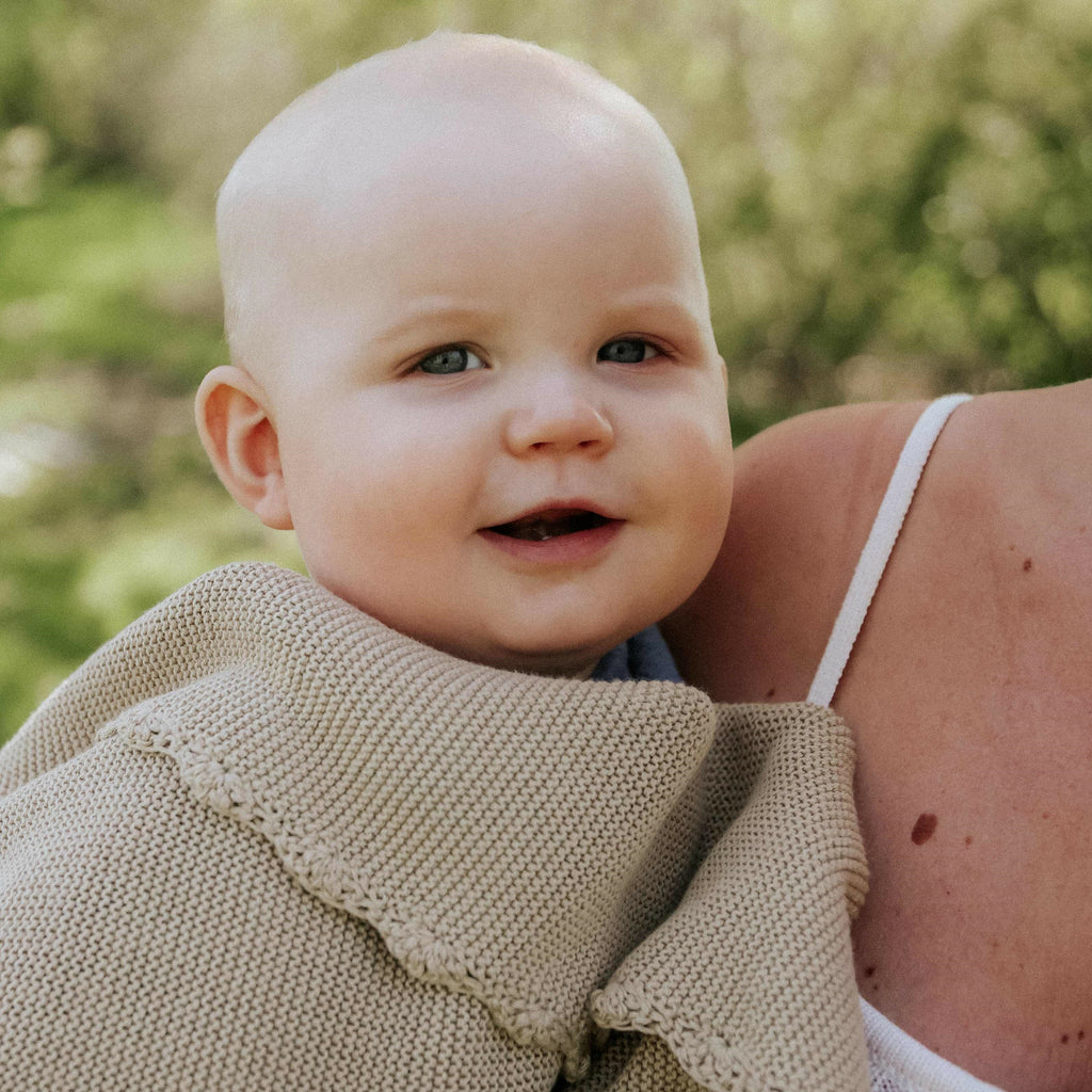 Baby with mother and knit beige blanket