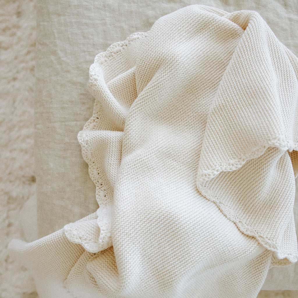 Cotton Knit Baby Blanket in Ivory laid out on rug to show the beautiful trim detail.